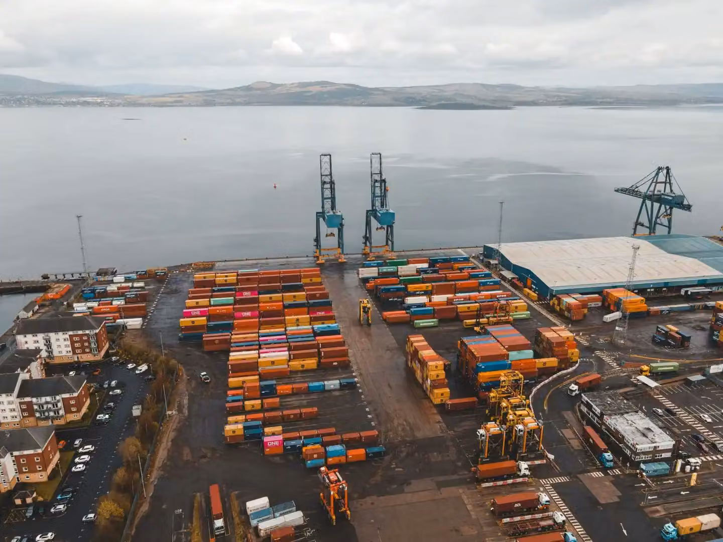 Aerial shot of a busy container port in Scotland with cranes and colorful cargo containers.